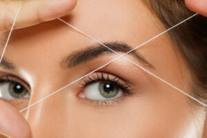 Close-up,Of,Female,Eye,With,A,Thread.,Eyebrow,Threading,-